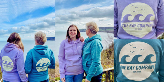 Two models wearing The Bay Company Wave Hoodie overlooking Robin Hood's Bay