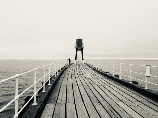 A print of a lone fisherman on the west pier of Whitby. 